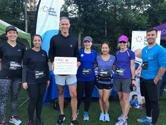 Seven people wearing athletic apparel stand shoulder to shoulder smiling at the camera