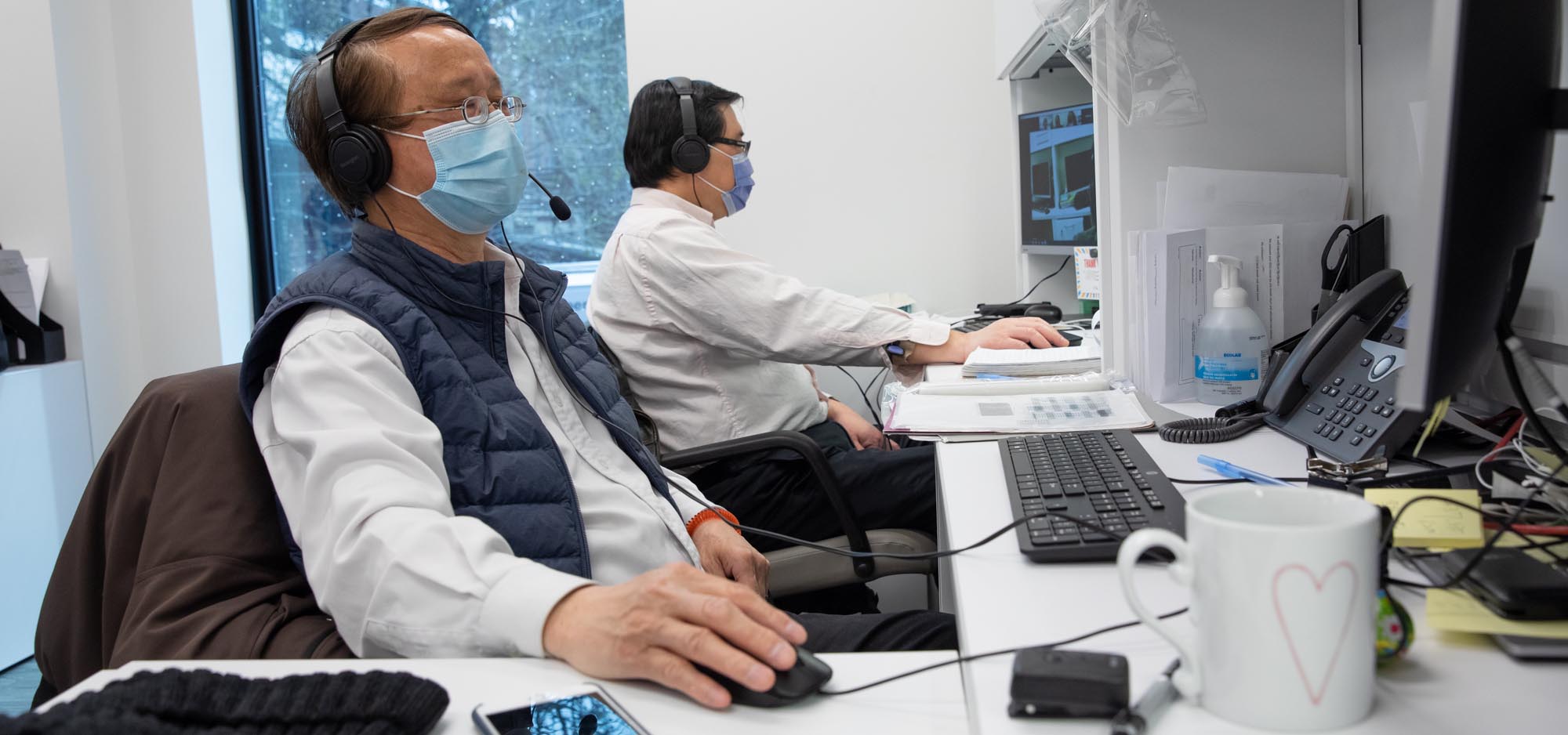 2 men in masks, looking at their computers