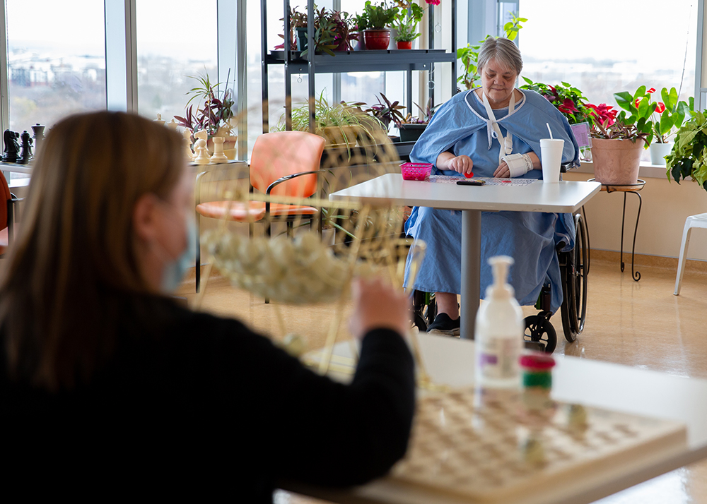 Patients doing activities such as painting and bingo in physically distanced environments