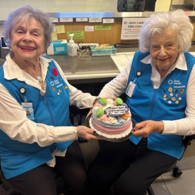 Two volunteers celebrating their birthdays with a cake.