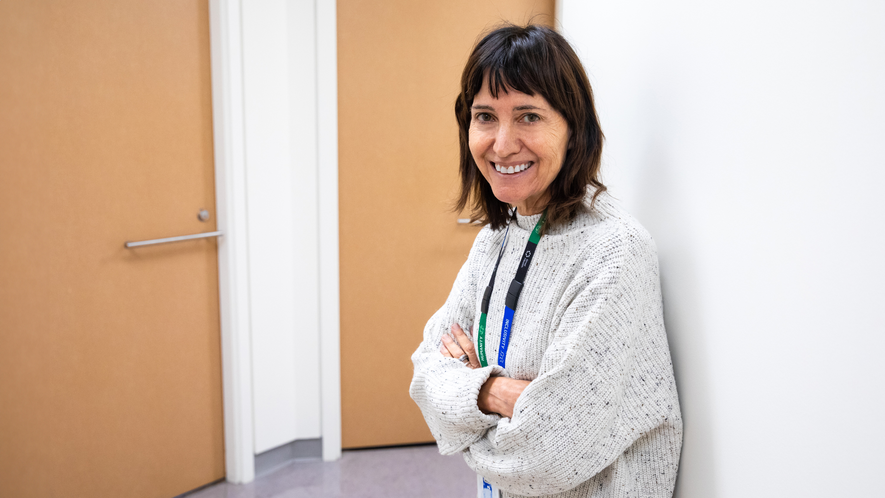 Dr. Denice Feig leaning against a wall in a white sweater.