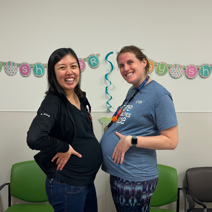 Two colleagues smiling and celebrating at their baby shower hosted by their team.