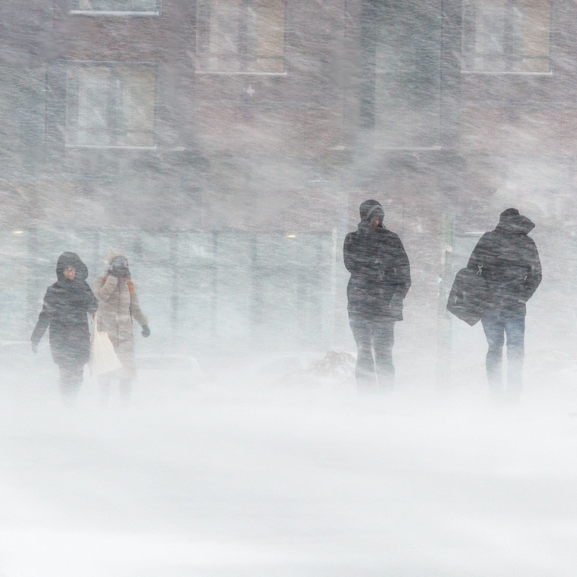 Four individuals walking in heavy snowfall.