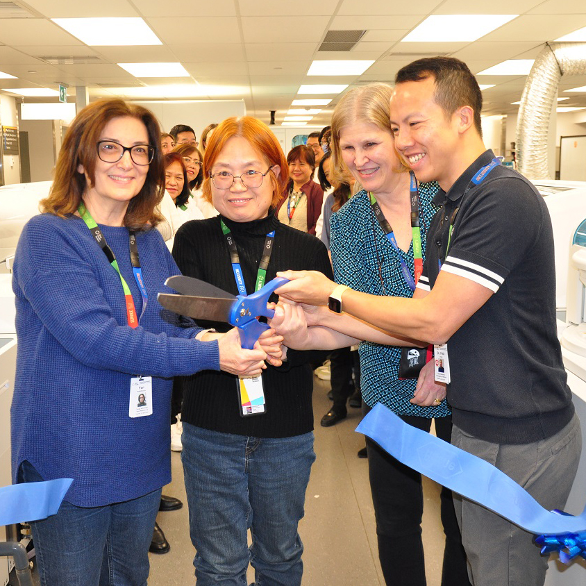 Four Sinai Health staff members cutting a ribbon with a large pair of scissors.