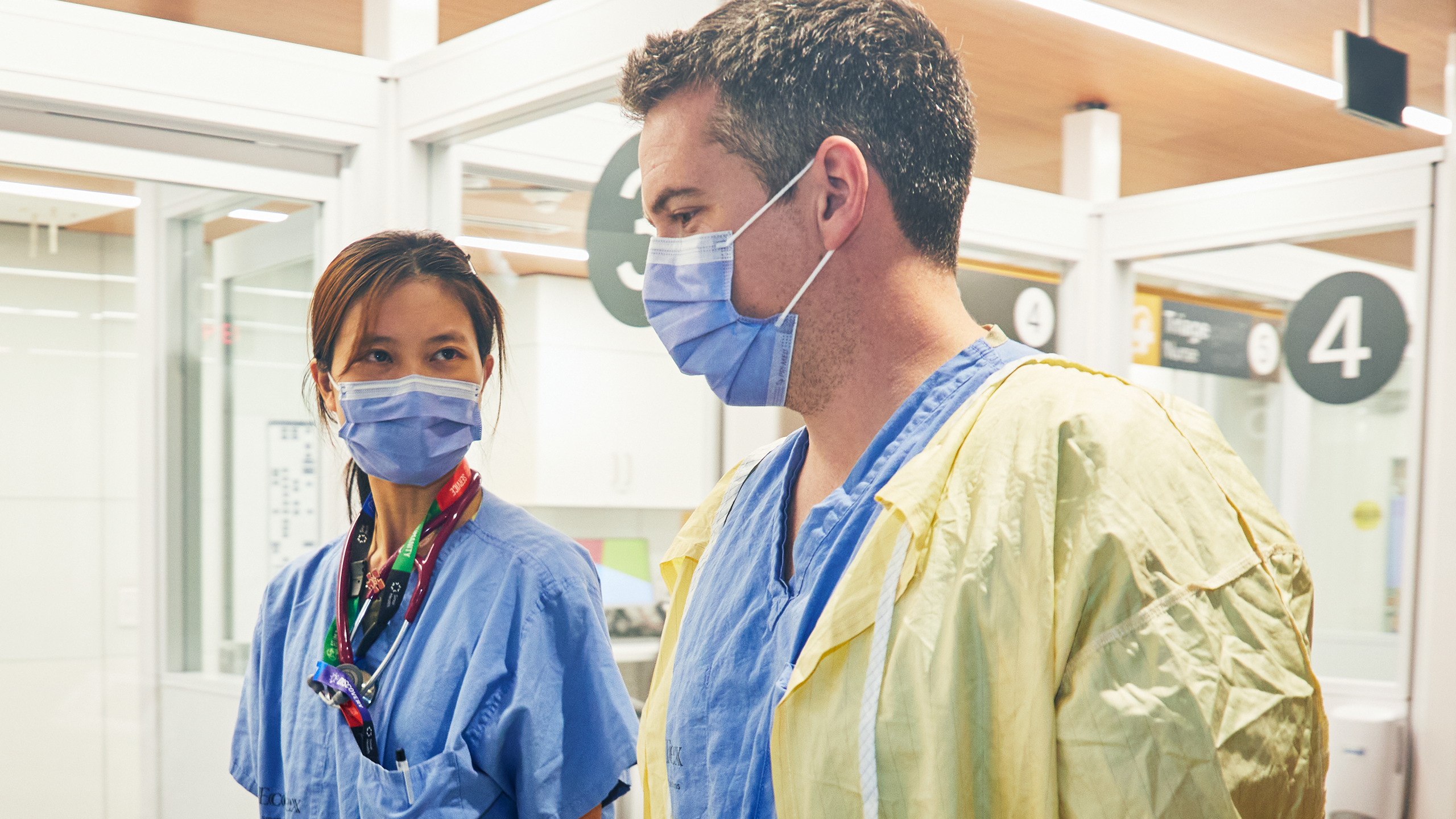 Female and male medical professionals talking while wearing face masks in emergency area