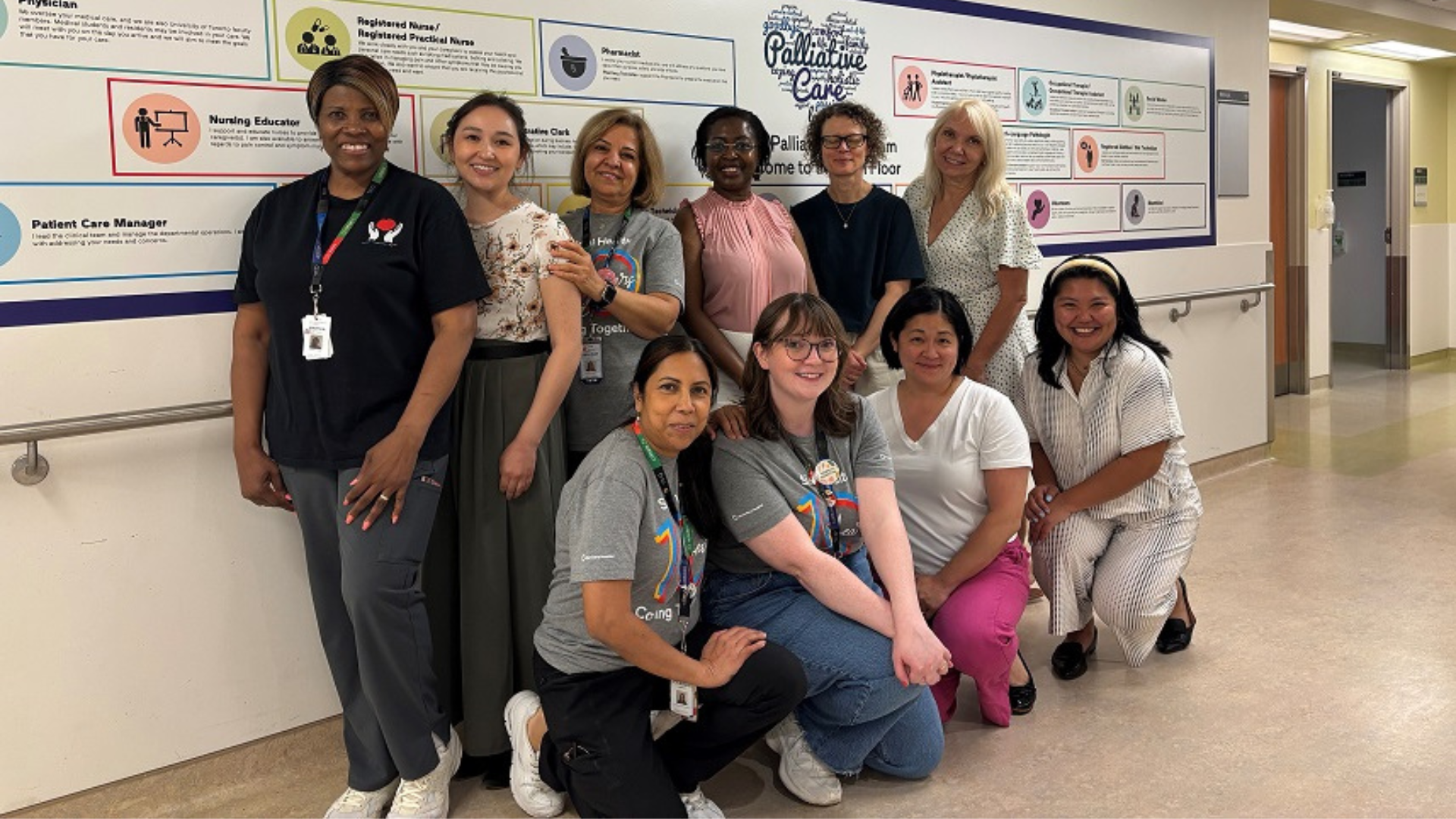 A group portrait of participants in a knowledge exchange session standing in a hospital corridor. They are looking at the camera and smiling.