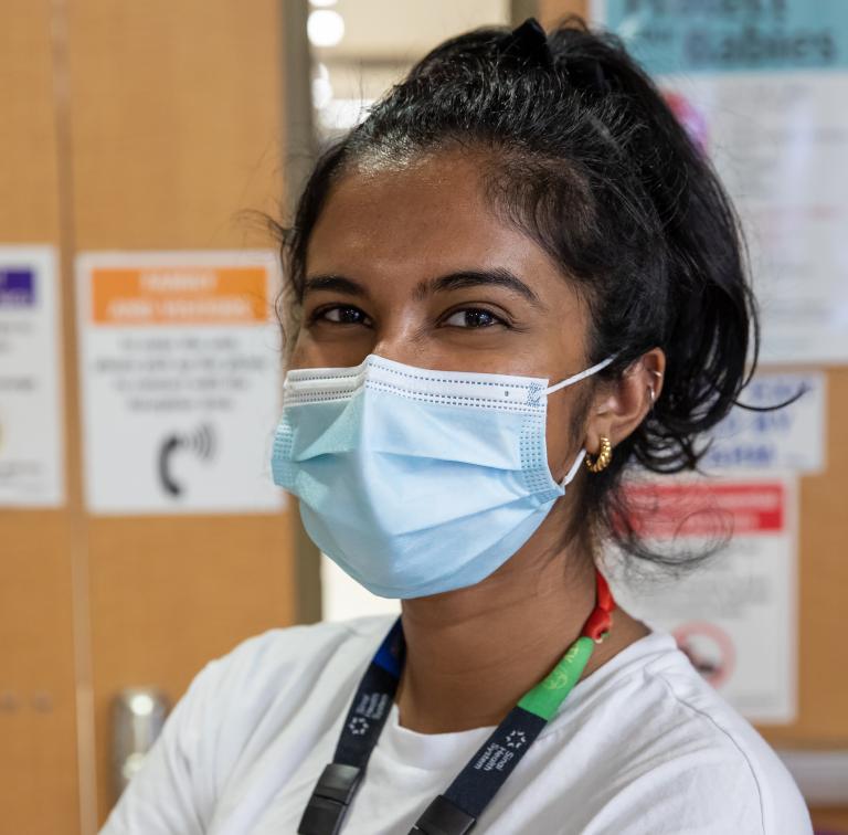 A nurse wearing a face mask looks at the camera