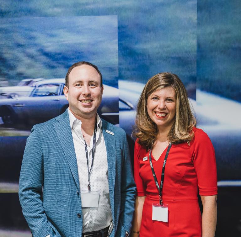 Man and woman standing in front of wall with a mural of a car