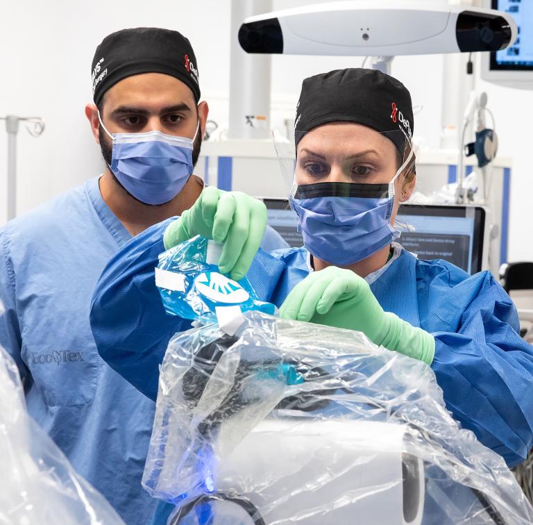 Two surgeons setting up robotic equipment in an operating room 