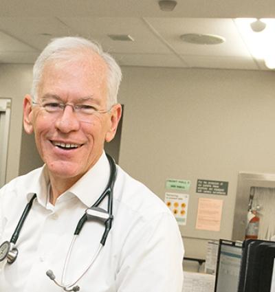 Photo is head shot of Dr. Don Melady with stethoscope on. Emergency Department is visible in the background