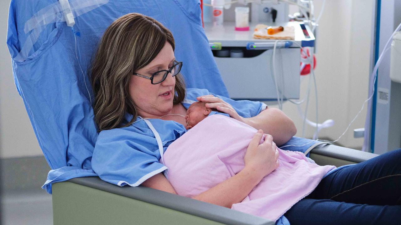 Mother sitting in a hospital chair with her infant laying on her chest