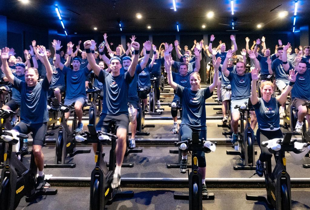 A group of people on spin bikes with their arms up in celebration