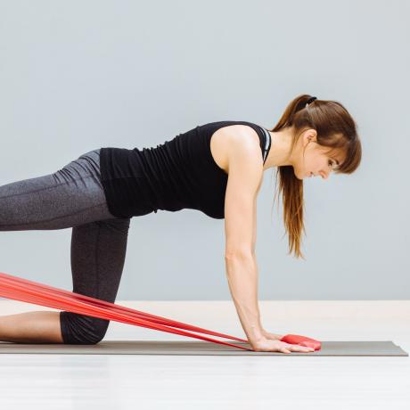 A woman performs a pilates exercise using an exercise band