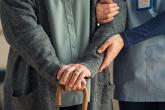 Health-care worker holds the arm of someone with a cane