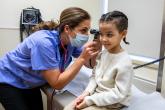 A family physician looks into a child's ear with an otoscope