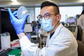 A laboratory scientist holds up a sample 