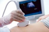 A technician performs an ultrasound on a pregnant patient