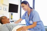 A physician smiles at a patient who is laying down in a hospital bed