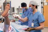 A care team member prepares a patient's leg for knee surgery