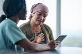 A health-care provider shows a female patient information on a tablet