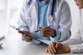 A physician speaks with a patient while holding a clipboard