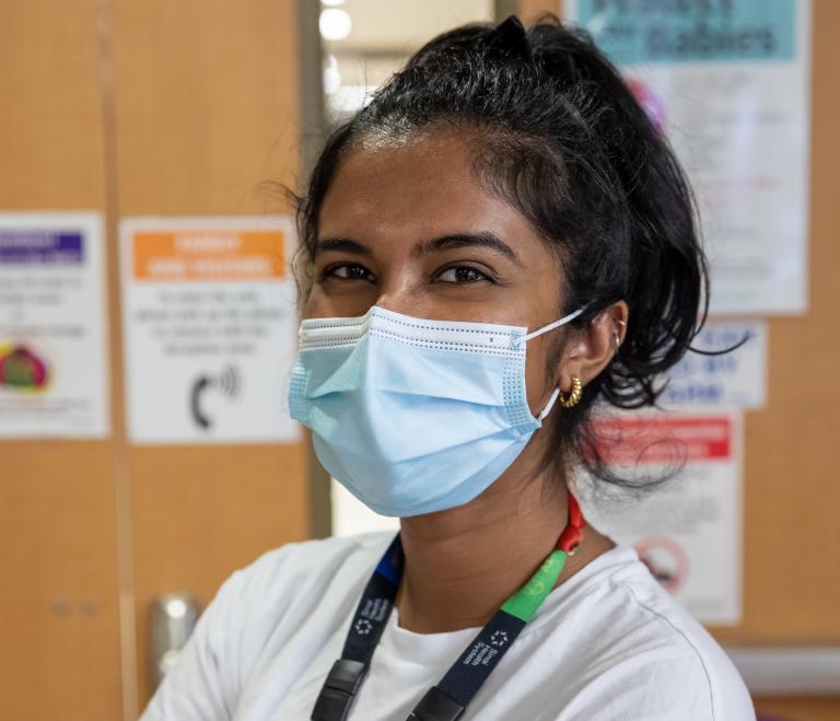 A nurse wearing a face mask looks at the camera