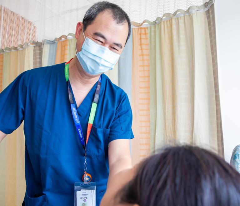 A nurse talks to a patient who is laying down in a hospital bed