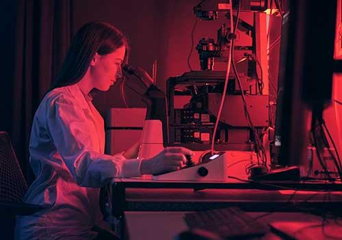 Woman sits in front of a microscope