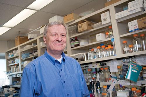 Man in blue button-up shirt stands in a medical lab