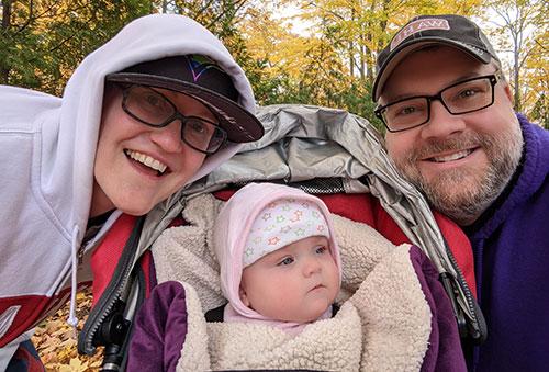 A mother and a father smile with their baby.