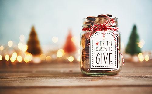 Masons jar full of coins, with a label that says, "'tis the season to give"