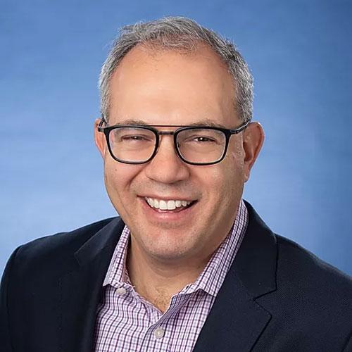 headshot of smiling man wearing glasses