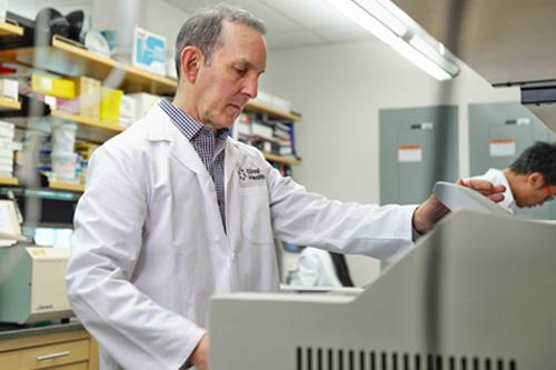 Man in white lab coat stands in front of medical equipment