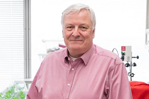 A man with white hair smiling