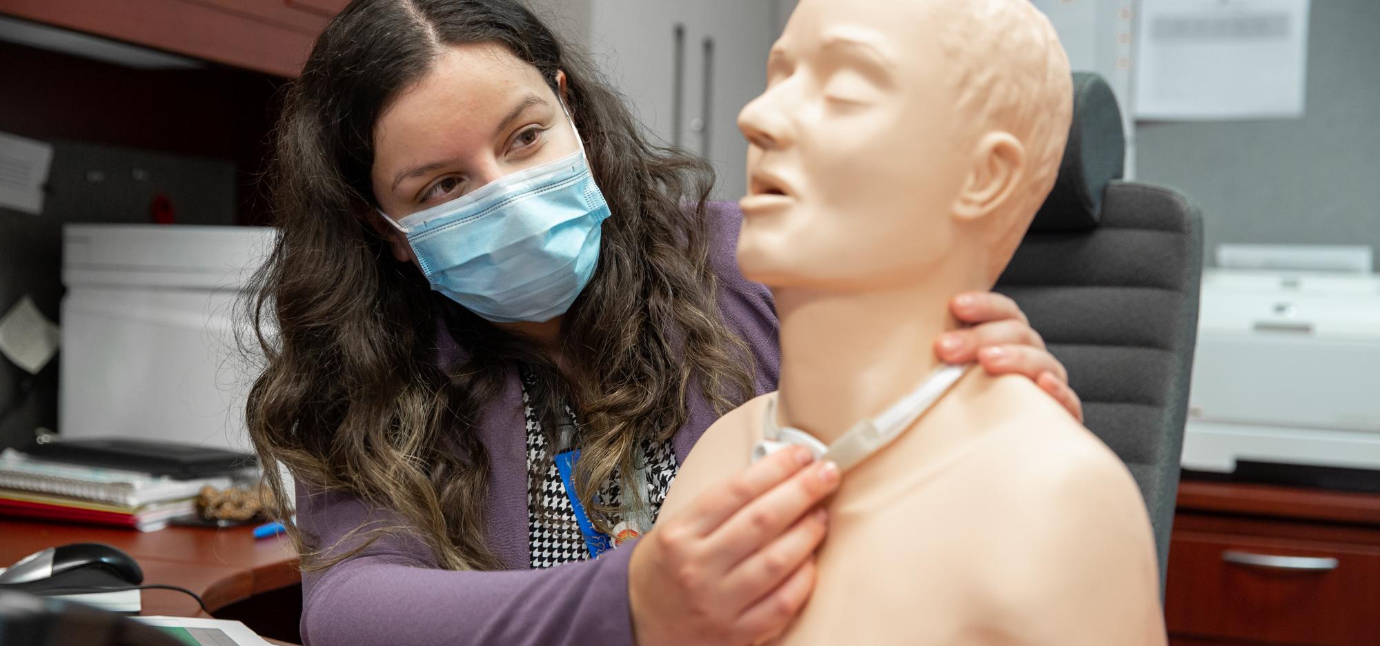 Sarabeth Silver holds a mannequin used for tracheostomy education