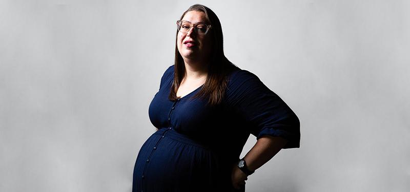 a bespectacled and visibly pregnant woman