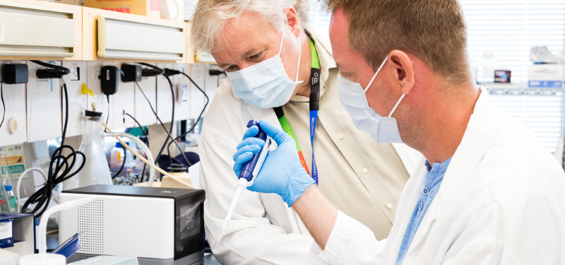 Dr. Jeff Wrana observes a colleague performing a test in the lab.