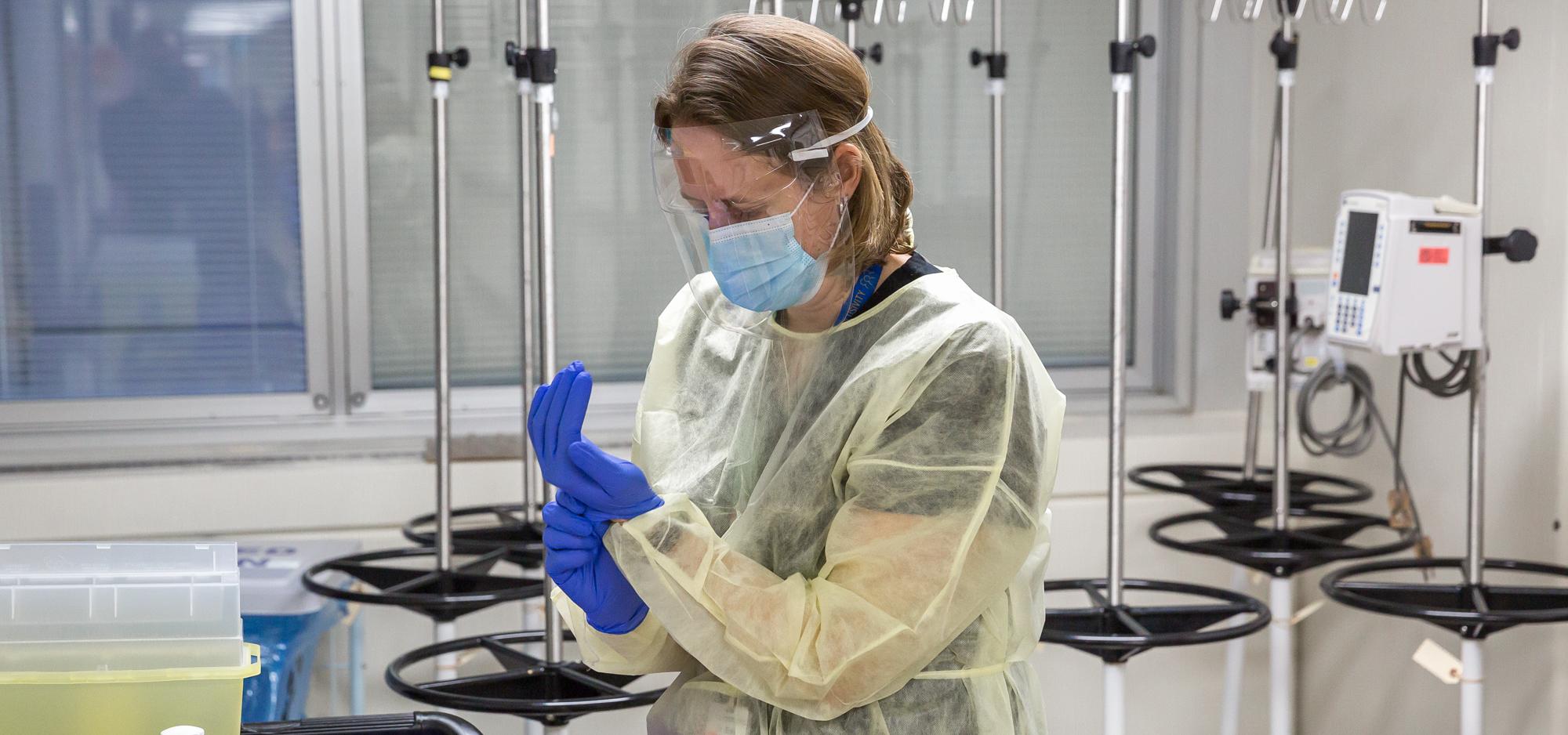 Dr. Erin Bearss dons personal protective equipment to administer the COVID-19 vaccine.