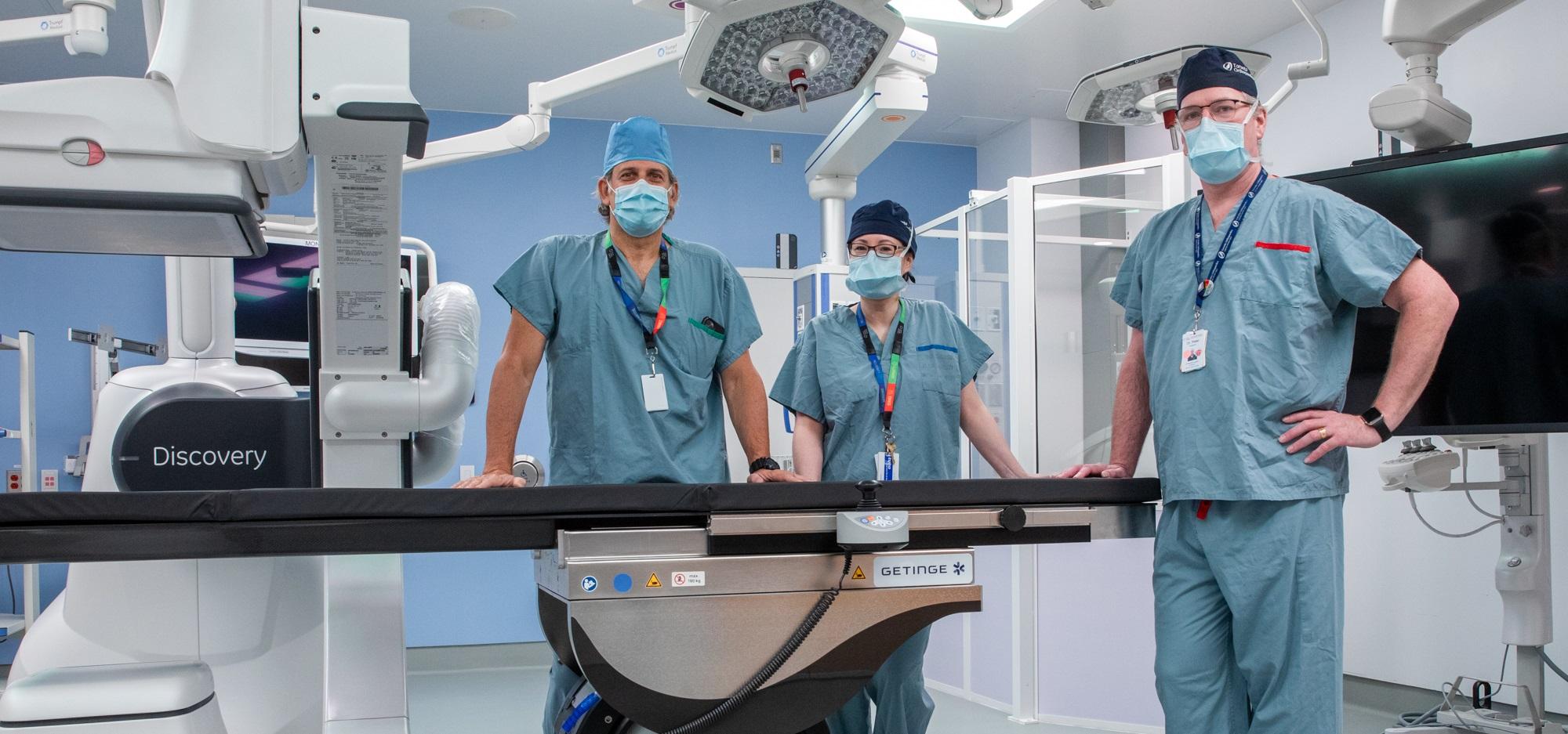 Three surgeons posing by an operating table