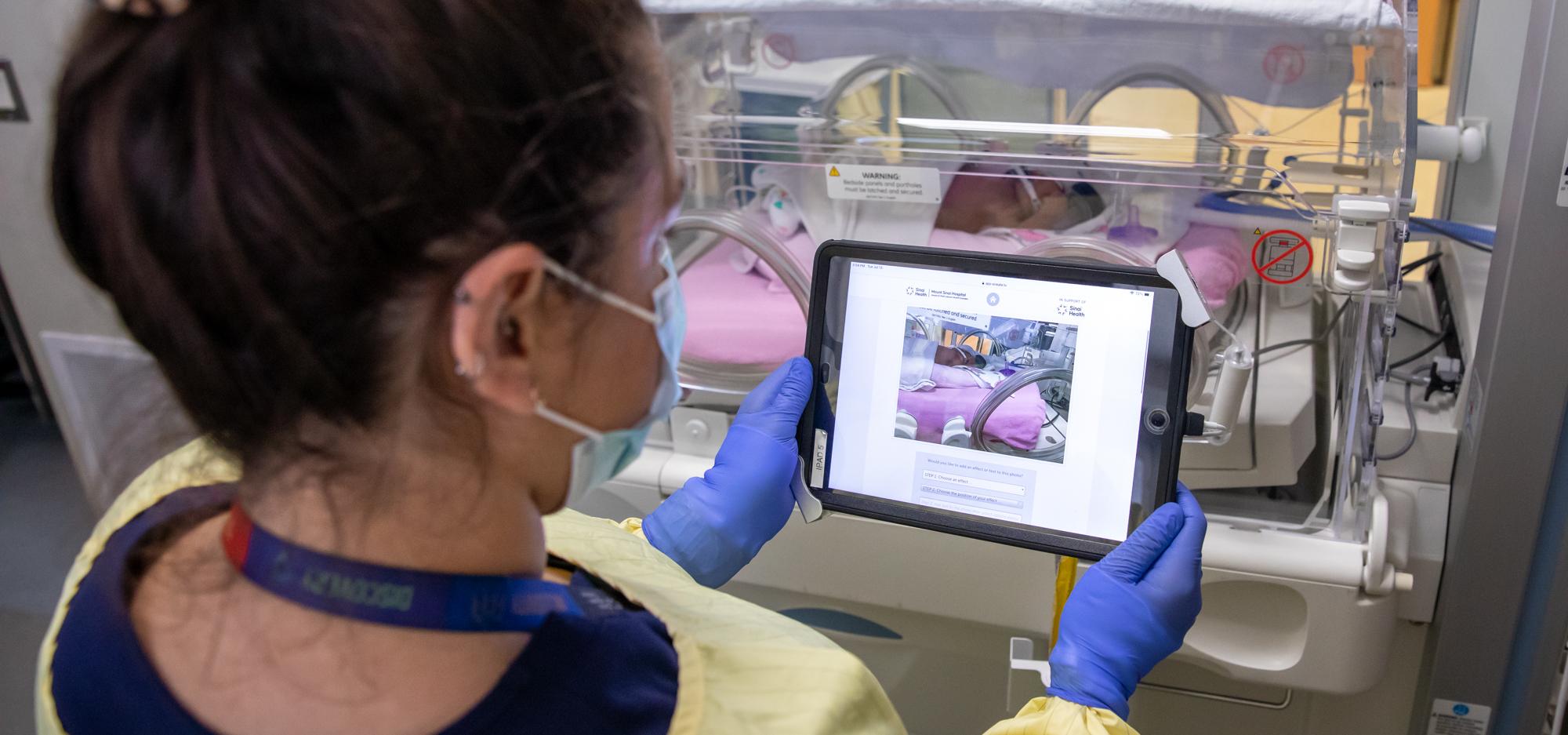 Woman with a tablet device in front of a premature baby at Mount Sinai Hospital