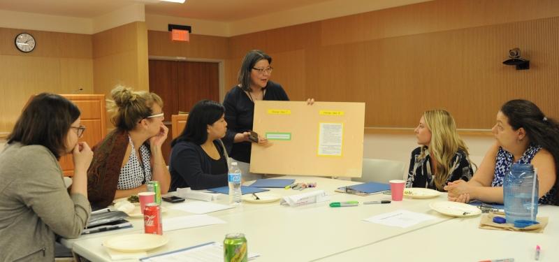 A group of people at a table looking at a board held by a person