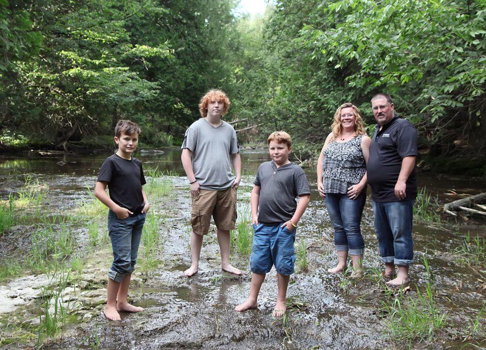 The Tummers family standing together in shallow river.