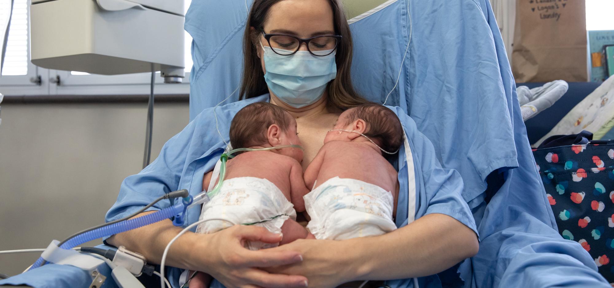 A mother breastfeeding her twin babies