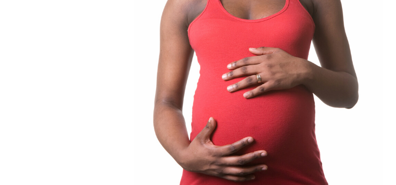 Pregnant woman in red shirt holding belly.