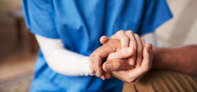 Health care working holding a patient's hand