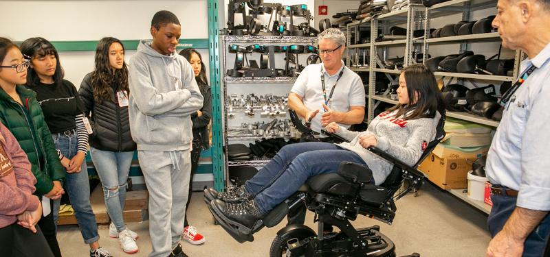 Children examining motorized chair with Sinai Health employees. 