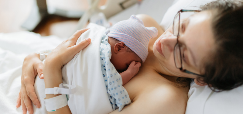 Mother holding her newborn baby in hospital bed