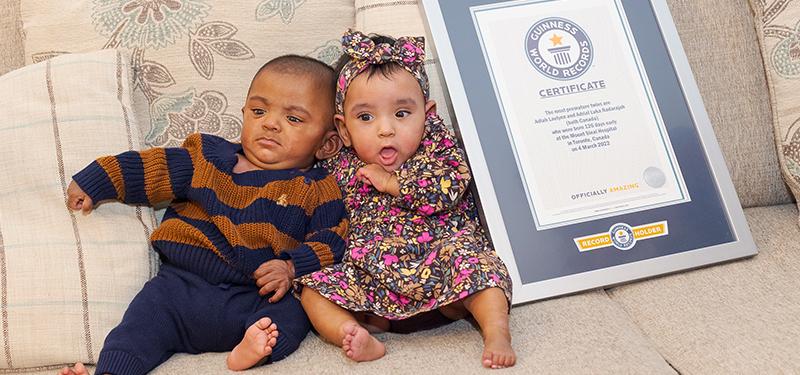 The world’s most premature twins sitting on a sofa next to their Guinness Record Certificate