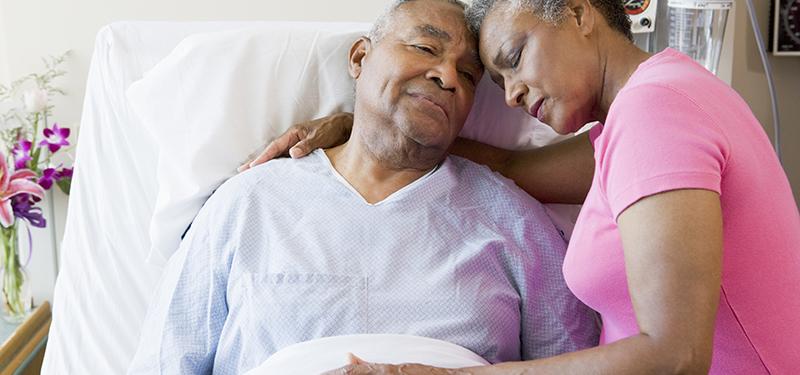 Woman comforting man in hospital bed