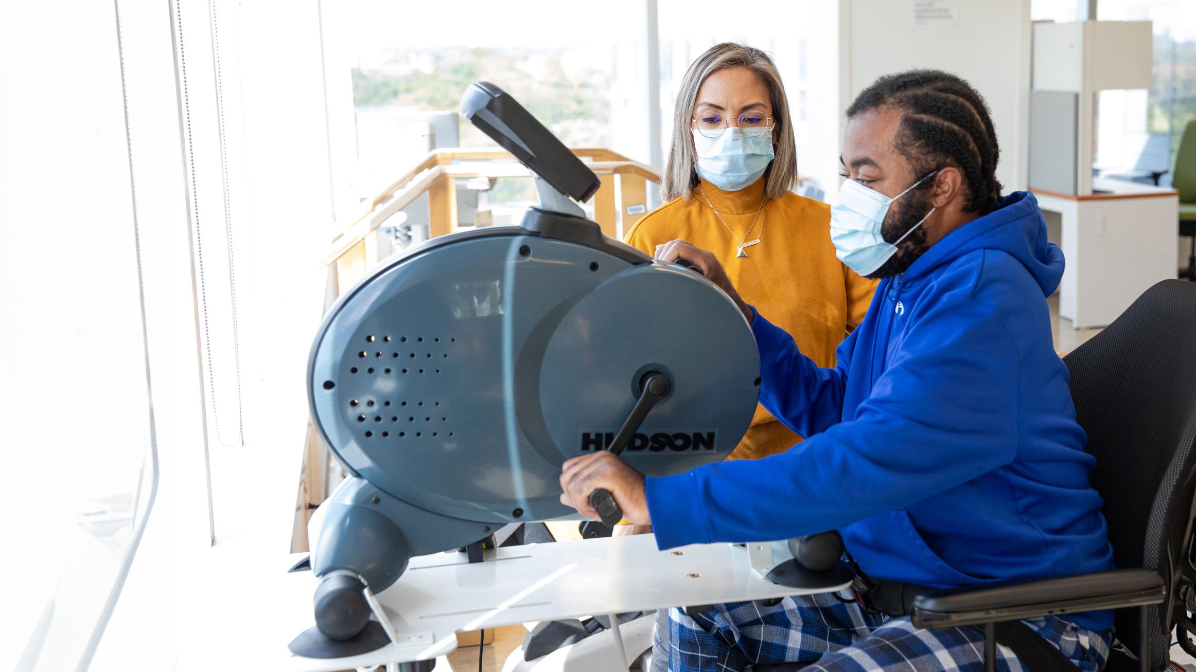 An occupational therapist helps a patient use exercise equipment